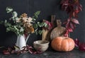 Autumn cozy kitchen still life. Crockery, jug with eucalyptus branches, cutting boards, vine wreath, pumpkin on the table, on a Royalty Free Stock Photo