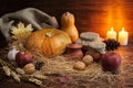 autumn dark Thanksgiving concept with pumpkins, red apple, garlic, cone, nut, jug, straw and burning candles on wooden Royalty Free Stock Photo