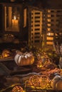 Autumn decoration with white pumpkins, lights, blanket and dried leaves on a terrace or patio in night Royalty Free Stock Photo