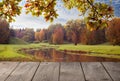 Autumn desk space, a free wooden table and a panorama of the autumn park in the season of leaf fall