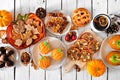 Autumn desserts table scene with a variety of sweet fall treats over white wood