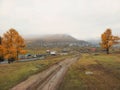 Autumn dirt road from a hill to a remote village Royalty Free Stock Photo