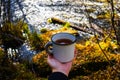 Autumn drink. Enameled cup of coffee or tea on autumn landscape outdoors