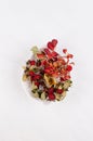 Autumn elegant background with red dried berries and leaves rose hip  in leaf bowl on soft light white wood board, top view. Royalty Free Stock Photo