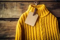 Autumn essentials, Yellow knitted sweater with price tag on rustic wooden background