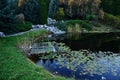 Autumn evening at water lilly pond with alpine garden, decorative trees and drain channel. Royalty Free Stock Photo