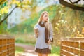 Fall concept - beautiful woman drinking coffee in autumn park under fall foliage Royalty Free Stock Photo