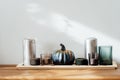 Autumn, fall cozy composition. Gray pumpkin with sequins and burning candles on the wooden tray on the table with white wall