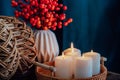 Autumn fall cozy mood composition for hygge home decor. Part of wicker pumpkin, burning candles on a tray and seasonal Royalty Free Stock Photo