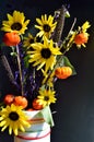 Autumn bouquet pumpkin on a stick sunflower millet grass purple filler white vase vertical