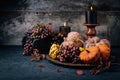 Autumn or fall harvest concept with lit candles, decorative pumpkins, corn, nuts, grapes and pinecones Royalty Free Stock Photo