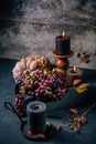 Autumn or fall harvest concept with lit candles, decorative pumpkins, corn, nuts, grapes and pinecones Royalty Free Stock Photo