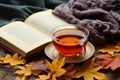 Autumn, fall leaves, cup of tea, opened book and warm scarf on wooden table. Seasonal, book reading, Sunday relaxing, teatime and