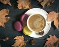 Autumn, fall leaves, hot steaming cup of cappuccino coffees, macaroons, cones on wooden table background. Royalty Free Stock Photo