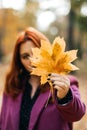 Autumn fashion, earth tones style, bright fall color palette. Portrait of red-haired girl in purple coat Royalty Free Stock Photo