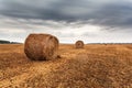 Autumn field with sheaves of hay and dramatic sky. Royalty Free Stock Photo