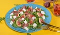 Autumn figs salad with arugula, feta, raw ham in blue plate on yellow background served with ros wine. Royalty Free Stock Photo