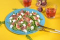 Autumn figs salad with arugula, feta, raw ham in blue plate on yellow background served with ros wine. Royalty Free Stock Photo