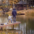 Autumn fishing, unrecognizable men and child, backs to us. Wooden pier, fishing bridge. Autumn park. Fallen leaves Royalty Free Stock Photo