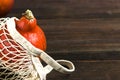 Autumn flat composition with orange pumpkins in a mesh shopping bag on a wooden background. Creative Autumn, Thanksgiving Day,