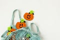 Autumn flat lay composition with orange felt pumpkins in mesh shopping bag on white background. Creative autumn, thanksgiving,