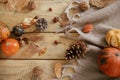 Autumn flat lay. Cute pumpkins, autumn leaves, cones, walnuts, cozy scarf on rustic wooden table in farmhouse. Fall in rural home