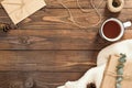 Autumn flatlay composition. Frame made of craft paper envelope, cup of tea, rope, gift box, white knitted scarf on wooden