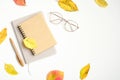 Autumn flatlay composition. Women fashion glasses, paper notebook, fallen leaves on white background. Hygge, cozy home office desk