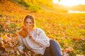 Autumn flirty blonde girl dreamy posing in November day. Outdoor photo of a pleased long-haired woman sitting on the