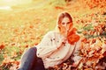 Autumn flirty blonde girl dreamy posing in November day. Outdoor photo of a pleased long-haired woman sitting on the