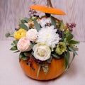 Autumn floral bouquet in a pumpkin vase on a light background, a mixture of flowers, pionic rose, eucalyptus