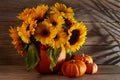 Autumn flowers composition in a pumpkin vase with pumpkins on wooden background Royalty Free Stock Photo