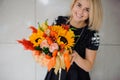 Autumn flowers in hands of woman. Pumpkin, sunflowers and other flowers