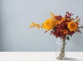 Autumn flowers of red, orange and yellow colors, chrysanthemum flowers, in a vase against a pale blue wall. Royalty Free Stock Photo