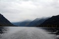 Autumn foggy landscape in Altai. A trace of a passing ship in Lake Teletskoye. Mountains in the fog.