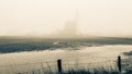 Autumn foggy morning, church of Den Hoorn behind the barbed wire. Texel island in the Netherlands, tinted photo Royalty Free Stock Photo