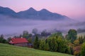 Autumn foggy morning in an old village with wooden houses under mountain peaks. Royalty Free Stock Photo