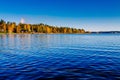 Autumn foliage, fall colorful forest over blue lake with red cabins in Finland Royalty Free Stock Photo