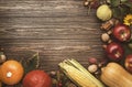 Autumn food top view, Thanksgiving or Halloween background: pumpkins, nuts, fallen leaves and spices on brown wooden background. Royalty Free Stock Photo