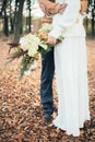 In the autumn forest the bridegroom embraces the bride, the bride holds a bouquet Royalty Free Stock Photo