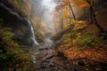 autumn forest hike with view of cascading waterfall and misty stream Royalty Free Stock Photo