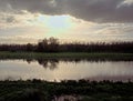 Autumn forest reflecting in a lake under a dramatic cloudy sky in the flemish countryside Royalty Free Stock Photo