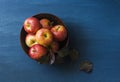 Autumn fresh red apples in a ceramic bowl on a blue background, top view.