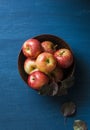 Autumn fresh red apples in a ceramic bowl on a blue background, top view.