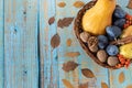 Autumn fruit in a wicker basket on a rustic wooden background with dry leaves and copy space Royalty Free Stock Photo