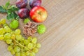 Autumn fruits, cone, chestnuts, apple, plum and grapes on wood b