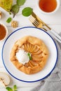 Autumn galette with pear, ice cream, walnuts, caramel sauce and cinnamon on a white wooden background