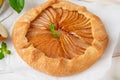 Autumn galette with pear, walnuts, caramel sauce and cinnamon on a white wooden background