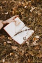 In the autumn grass covered with fallen dry leaves lies an open book of poetry, in it nested stem of grass and old medallyon Royalty Free Stock Photo