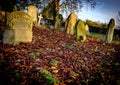 Autumn graveyard showing ancient graves within a carpet of fallen leaves.